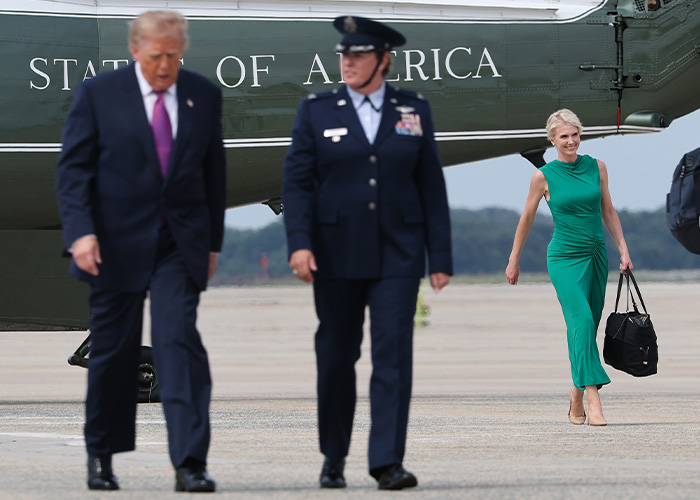 Trump aide Natalie Harp in a green dress on the tarmac behind Donald Trump
