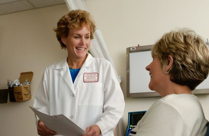 A smiling female doctor speaking with her patient in a clinic, representing historical medical practices.