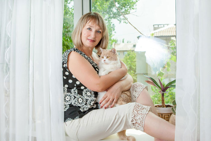 A woman holding her cat, looking directly at the camera, after her neighbors dogs attack her cat. A woman holding her cat, looking directly at the camera, after her neighbors dogs attack her cat.