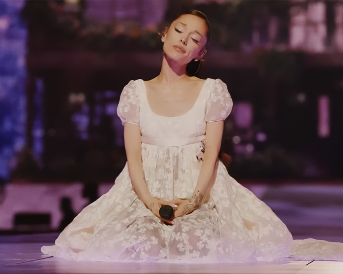 Ariana Grande in a white dress, showing a concerning detail.