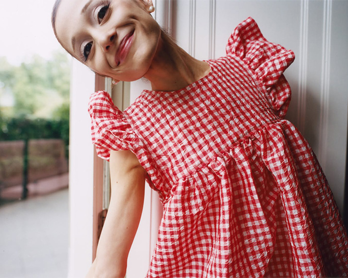 Ariana Grande smiling in a red and white checked dress, sparking worry among people.