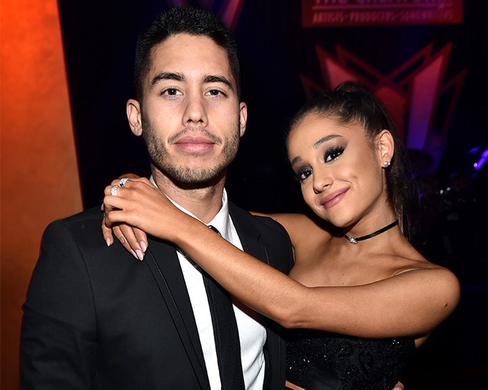 Ariana Grande poses with a man, and her appearance has spurred worry among fans. She is smiling.