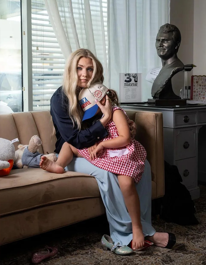 Erika Kirk sitting on a couch and holding a child in a red and white checkered dress Erika Kirk sitting on a couch and holding a child in a red and white checkered dress