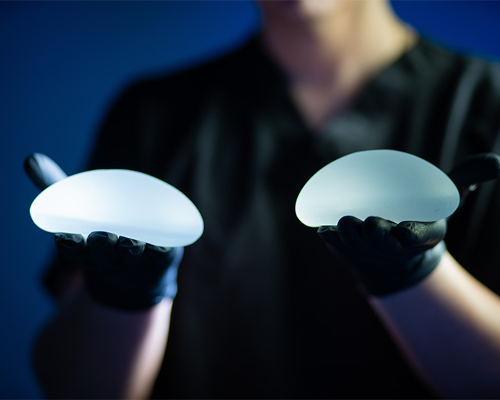 A pair of breast implants are shown, representing different sizes and the discussion around perfect breast shape.