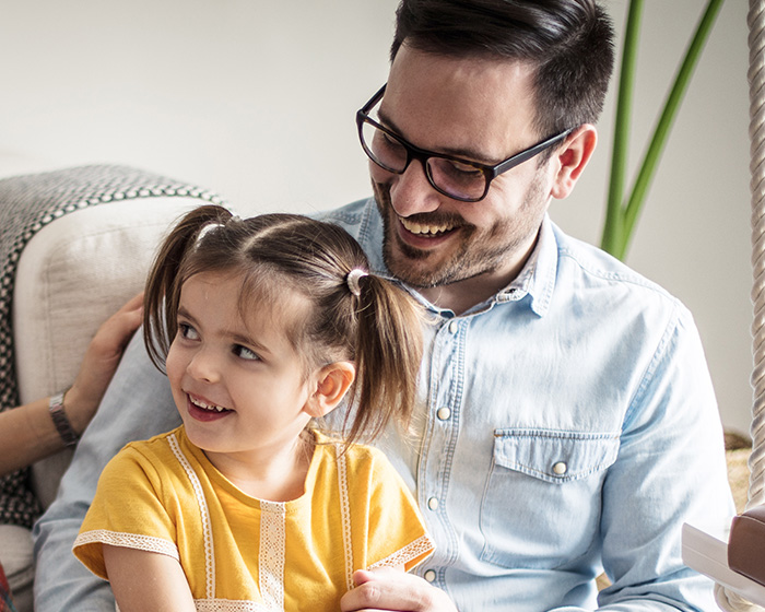 A happy father and daughter smiling together, highlighting the dad's active role in parenting.