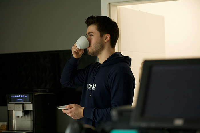 Worker drinking coffee next to an office coffee machine
