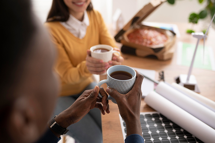 A worker enjoys a coffee cup at the office with a coworker during a lunch break.