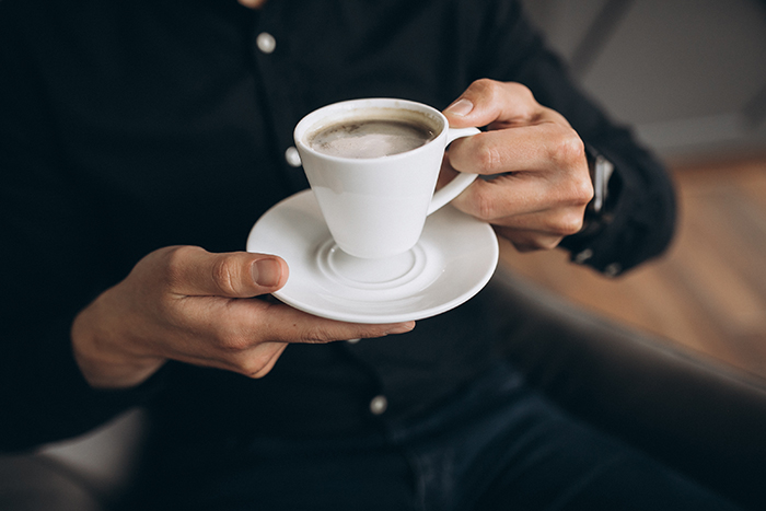 A man holds a fresh cup of espresso made from an office coffee machine.