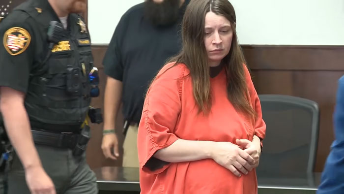 Ohio House of Horrors mom of 16 in orange jumpsuit walking in court, sparking pregnancy speculation.