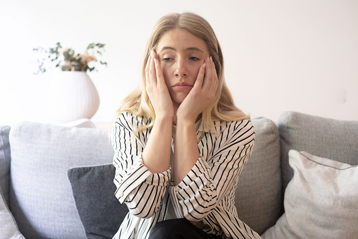 A sad young blonde woman holding her face, regretting her choices in an open relationship A sad young blonde woman holding her face, regretting her choices in an open relationship