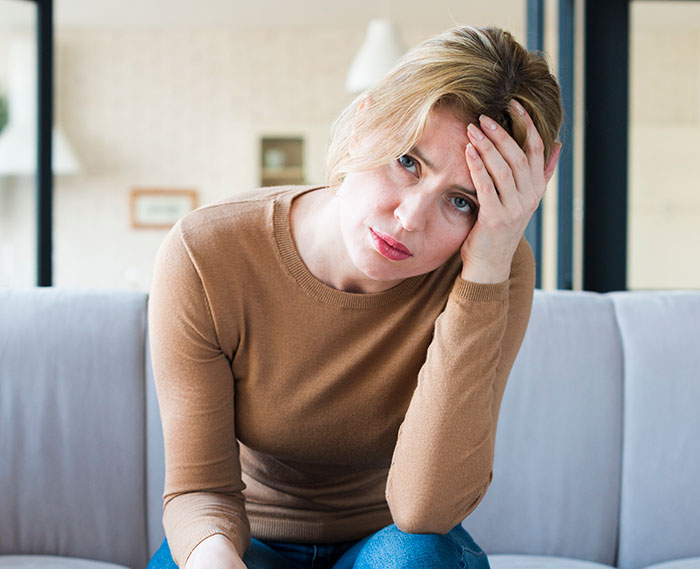A worried woman holding her head, reflecting on her open relationship decision A worried woman holding her head, reflecting on her open relationship decision