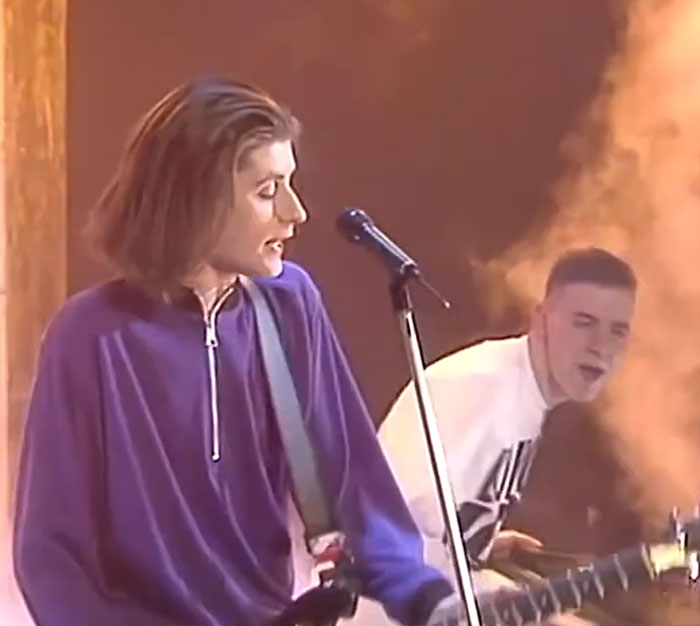 Musician with long hair performing on stage, showcasing famous celebrities who have unique fan encounters.