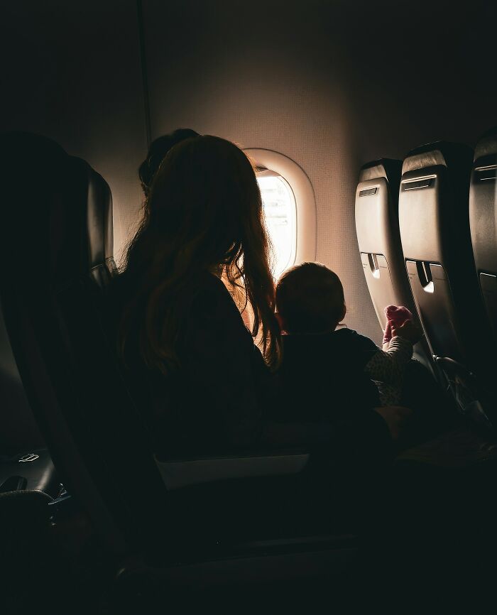 Mother and baby looking out a cabin window, illustrating things cabin crew deals with.