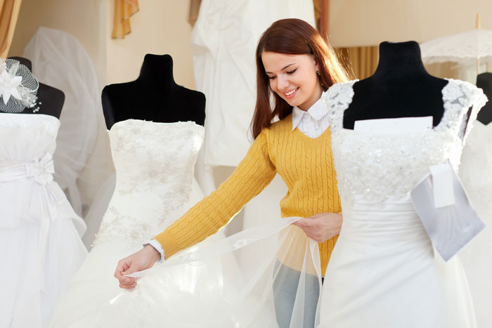 Happy woman looking at wedding dresses, despite her boyfriend going from minimum wage to $200K. Happy woman looking at wedding dresses, despite her boyfriend going from minimum wage to $200K.