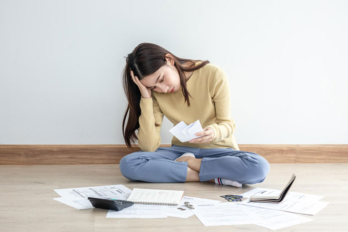 A woman sitting on the floor surrounded by papers and a calculator, looking stressed, contemplating her boyfriend's change regarding marriage after his income increase. A woman sitting on the floor surrounded by papers and a calculator, looking stressed, contemplating her boyfriend's change regarding marriage after his income increase.