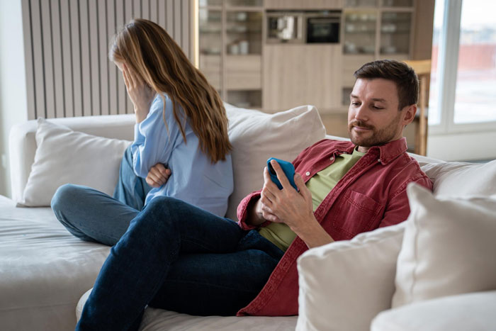 A guy on a couch checks his phone while his girlfriend, upset, faces away, illustrating the tension after he earned $200K and reconsidered marriage. A guy on a couch checks his phone while his girlfriend, upset, faces away, illustrating the tension after he earned $200K and reconsidered marriage.