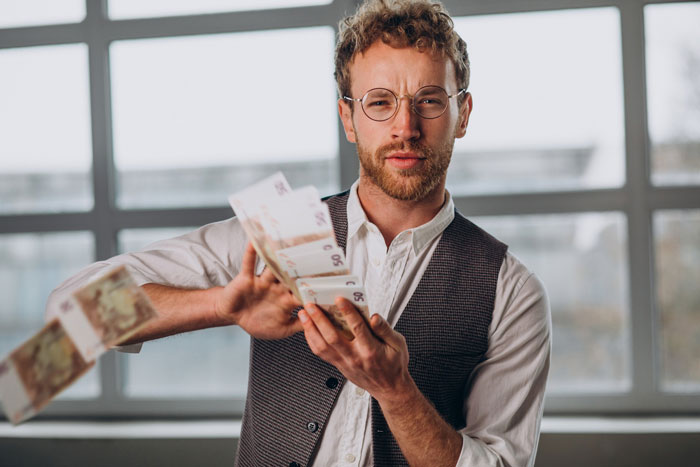 A man with glasses throwing money in the air after going from minimum wage to $200K. A man with glasses throwing money in the air after going from minimum wage to $200K.