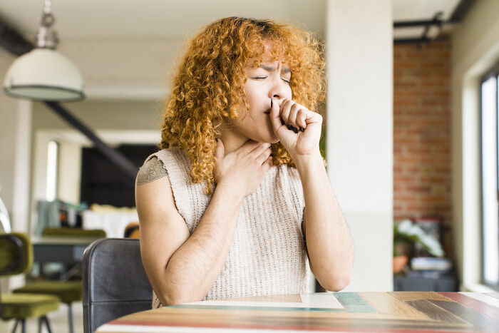 Woman with painful bloating and difficulty burping, clutching her throat.