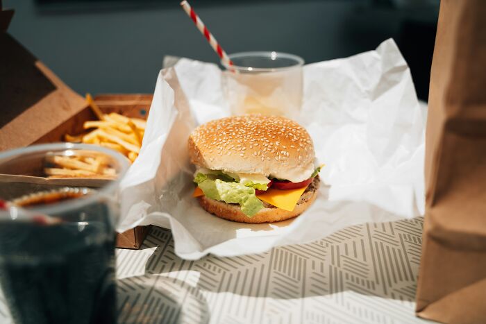 A burger and fries in takeout packaging, suggesting a quick meal when a 6th sense warns you to leave.