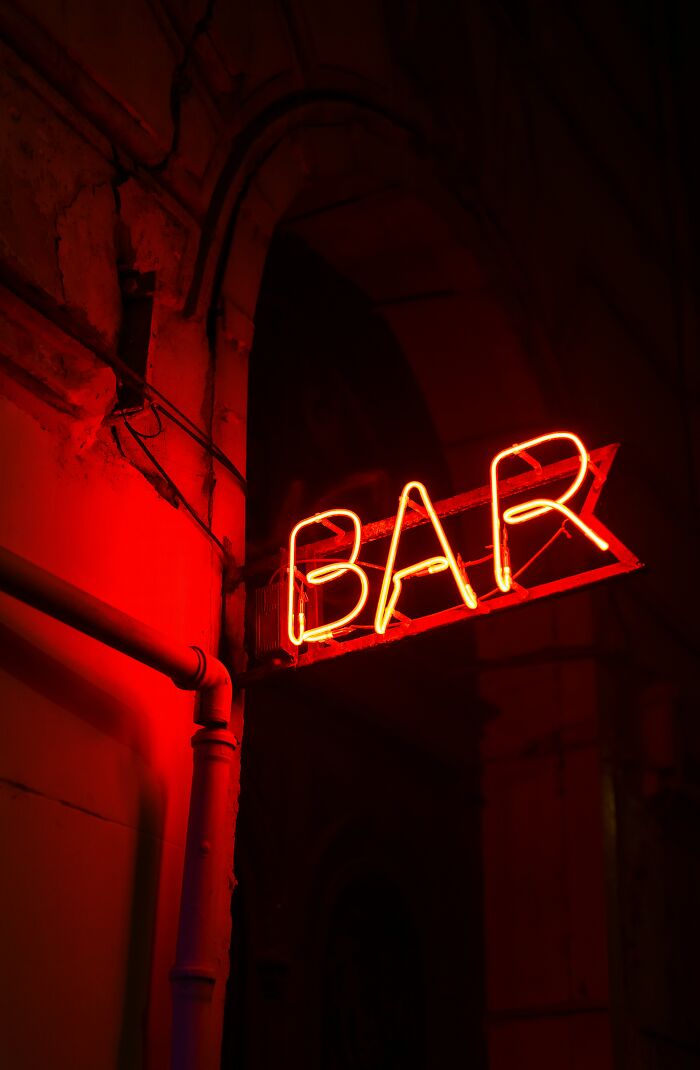 A red neon bar sign, illuminated at night, where a 6th sense could be crucial.
