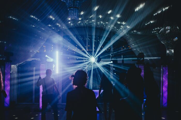 A group of people dancing in a nightclub with bright lights, a lively scene where a 6th sense is beneficial.
