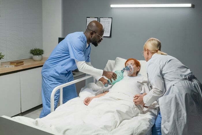 Medical staff assisting a patient in a hospital bed. The patient's sixth sense smells a rat.