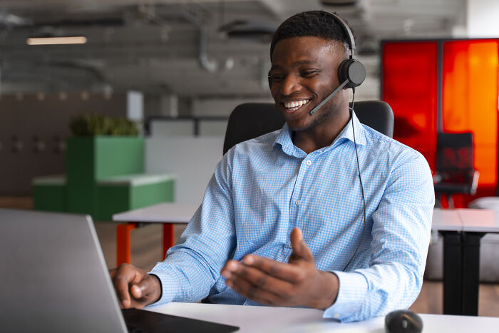 A smiling professional wearing a headset and using a laptop, discussing widely known industry secrets or professional insights.