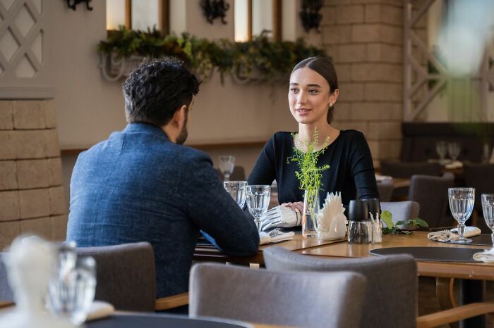 A couple sits at a restaurant table, depicting the aftermath when relationships fell apart.