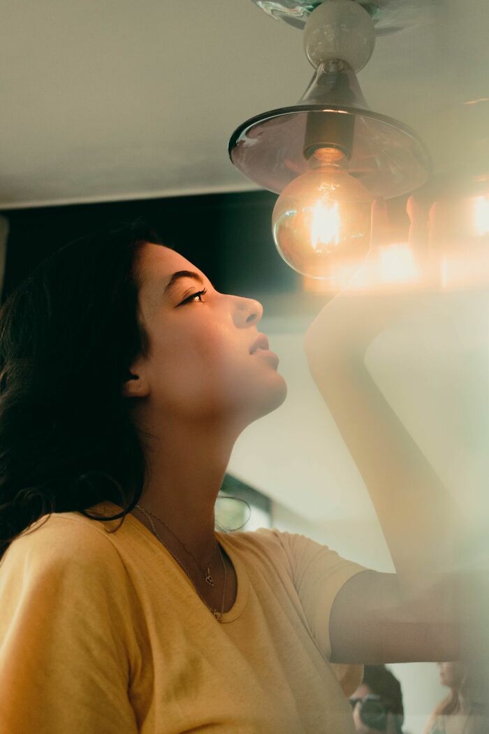 A woman looking up at a lightbulb, illustrating savage things people did after relationships fell apart.