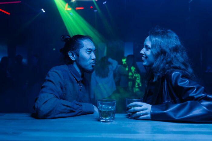 A man and a woman talking and laughing at a bar, possibly a new beginning after relationships fell apart.