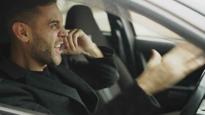 A man in a car, looking angry and shouting into a phone, depicting the aftermath of relationships falling apart.