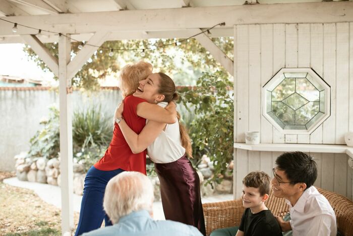 Two women embracing each other warmly, while others sit nearby, depicting savage things people did after relationships fell apart.