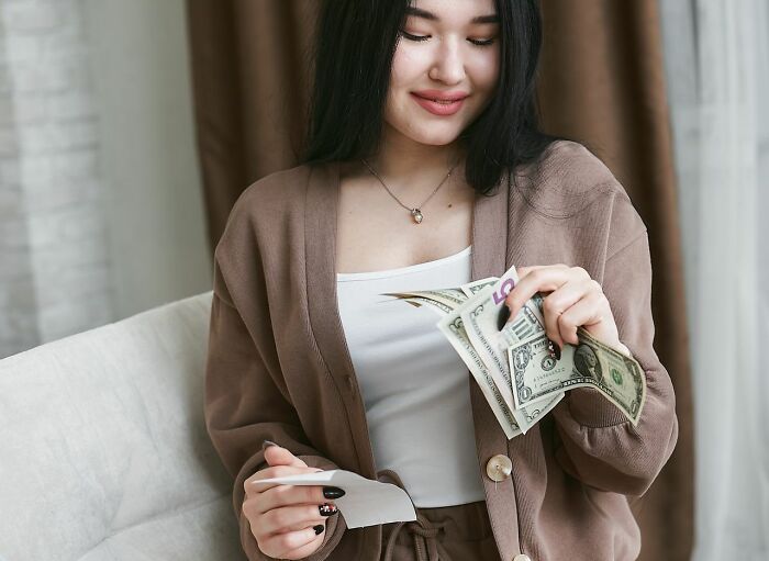 A woman happily holding money and a receipt, representing savage things people did after relationships fell apart.