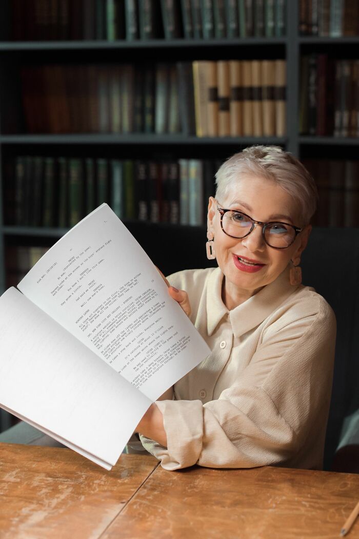A smiling woman holding an open book, showcasing stories of things people did after their relationships fell apart.