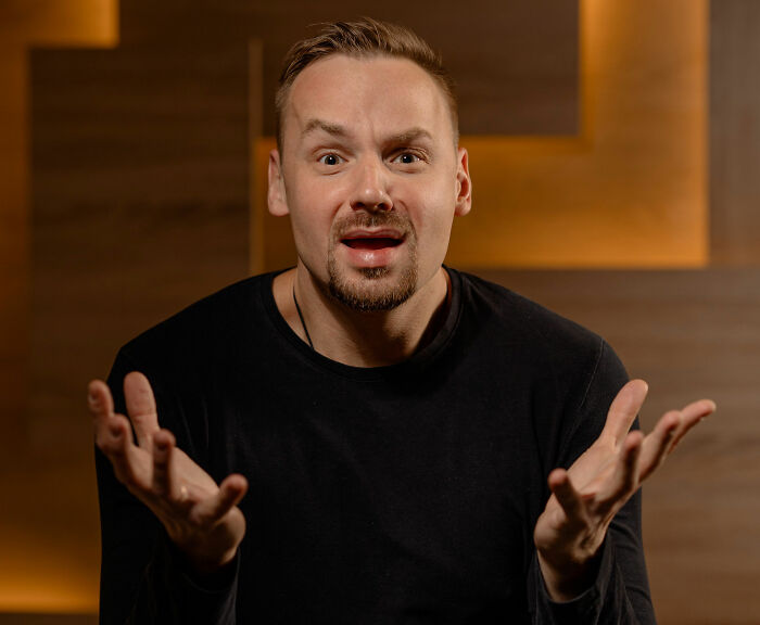 A man with a surprised expression and open hands, reacting to lies men told them.