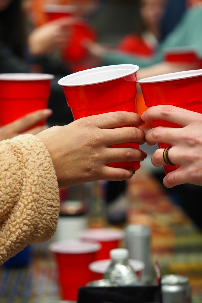Two people clinking red plastic cups, a typical scene associated with stereotypes about the US social gatherings.