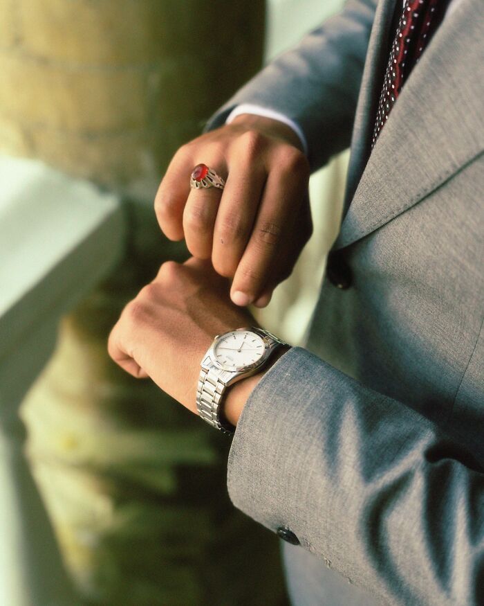 Man in a suit checking his watch, highlighting stereotypes about the US.