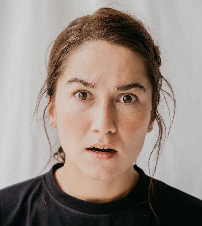 A woman with a shocked expression, eyes wide, reacting to crazy and unhinged lies.