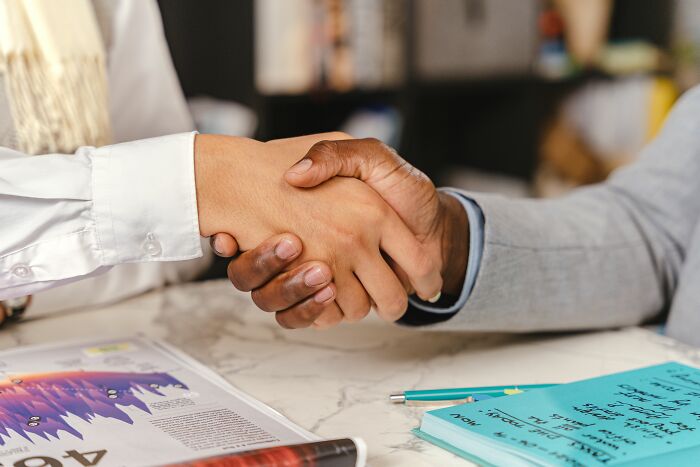 Two people shaking hands over documents, representing deals behind major scandals