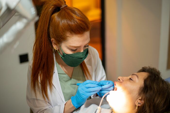 A dentist examining a patient's mouth, highlighting dental health symptoms doctors consider serious.
