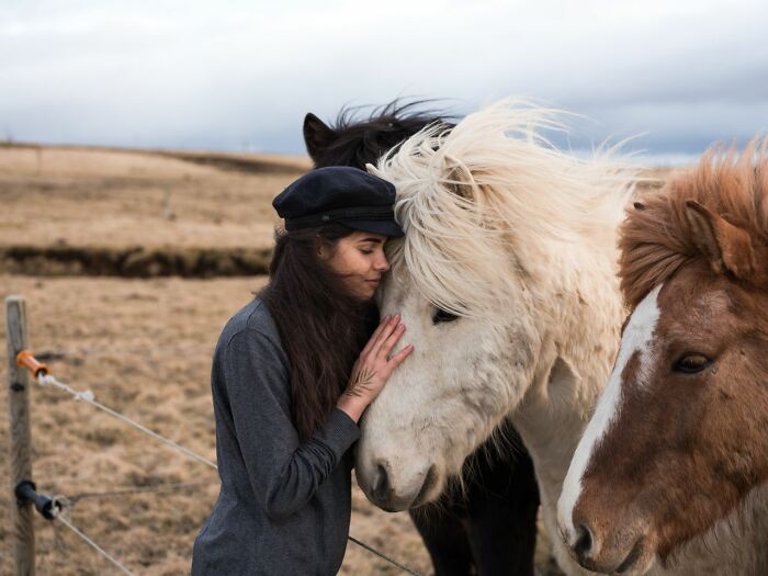 A woman affectionately petting a white horse, showcasing people enjoying moments with animals.