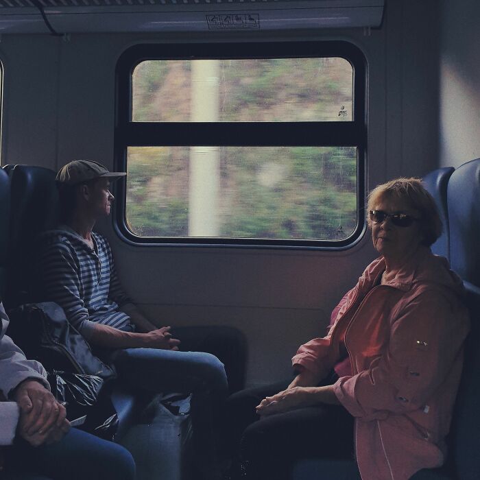 A man and an older woman on a train, looking out the window, demonstrating people overheard.