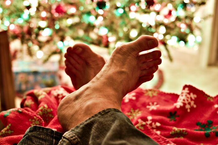 Feet resting on a red blanket near a Christmas tree, illustrating pure nightmare seatmate stories during airline seating.