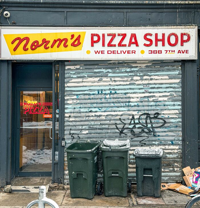 Closed pizza shop with graffiti and trash bins outside