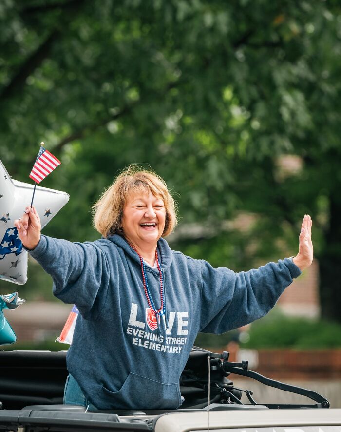 Woman waving an American flag, symbolizing stereotypes about the US.