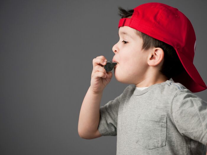 A young boy wearing a red baseball cap blowing a whistle, illustrating a specific childhood belief or game.