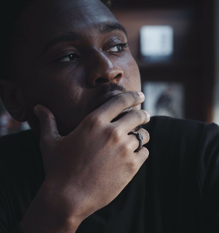 A man with a thoughtful expression, hand on his chin, possibly a therapist reflecting on a sociopath encounter.