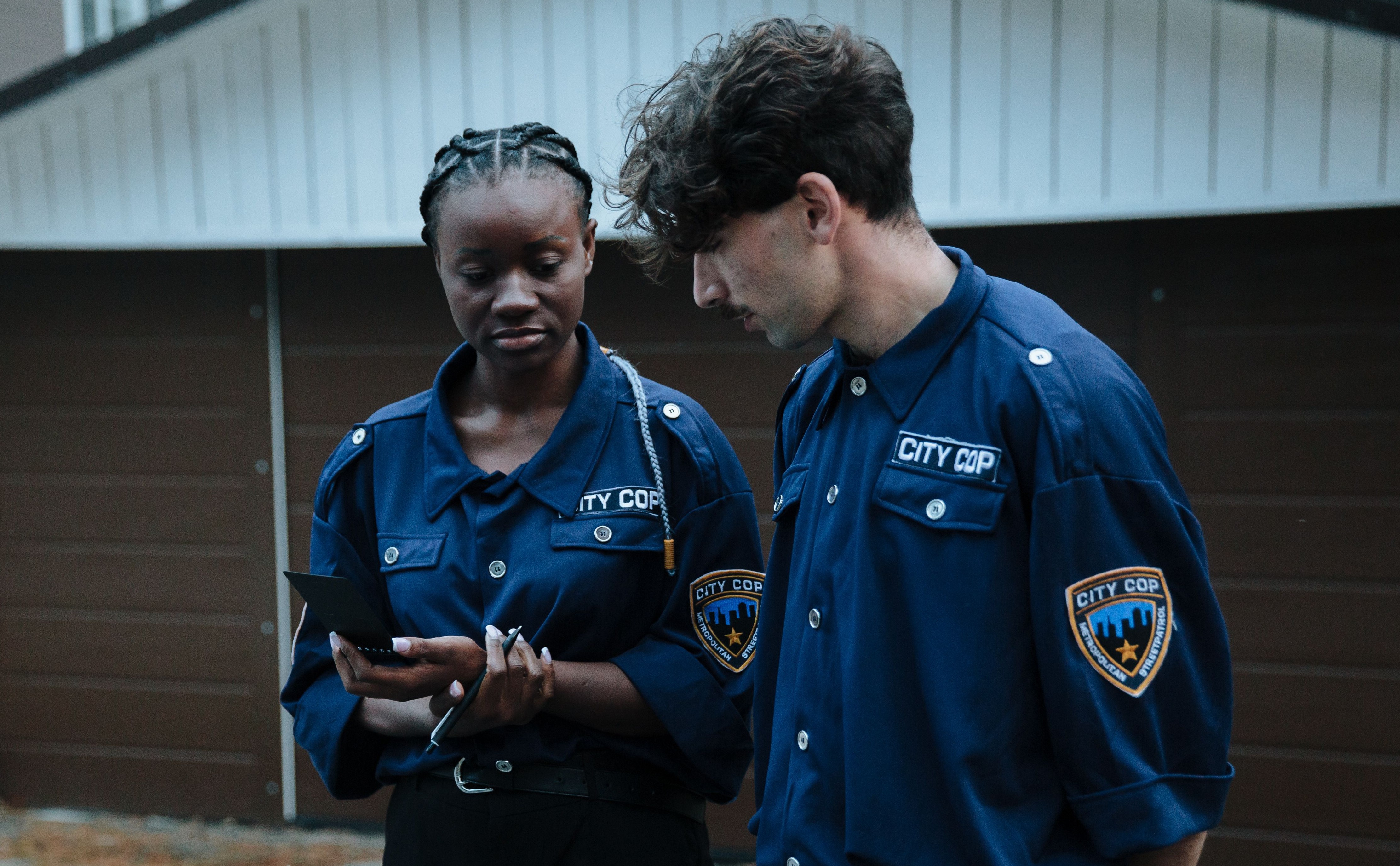 Two city cop officers looking at a notepad outside a house where a credit card thief was found