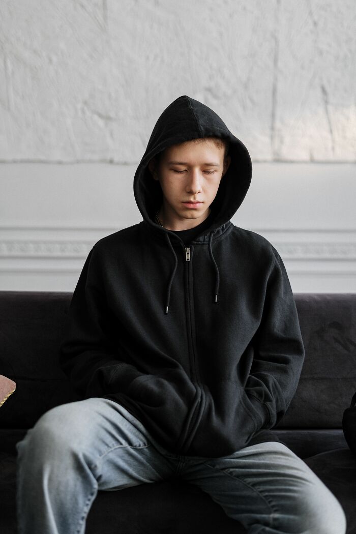 A young boy in a black hoodie sits with eyes closed, illustrating children who are struggling.