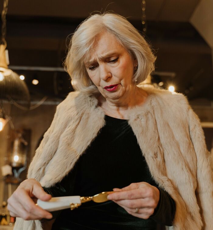 A rich woman in a fur coat looking at an expensive item
